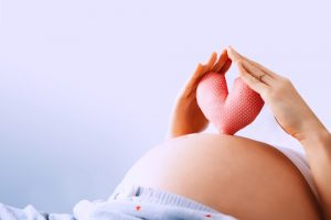 Pregnant,Woman,Holds,In,Palms,Symbol,In,Heart,Shape.,Loving